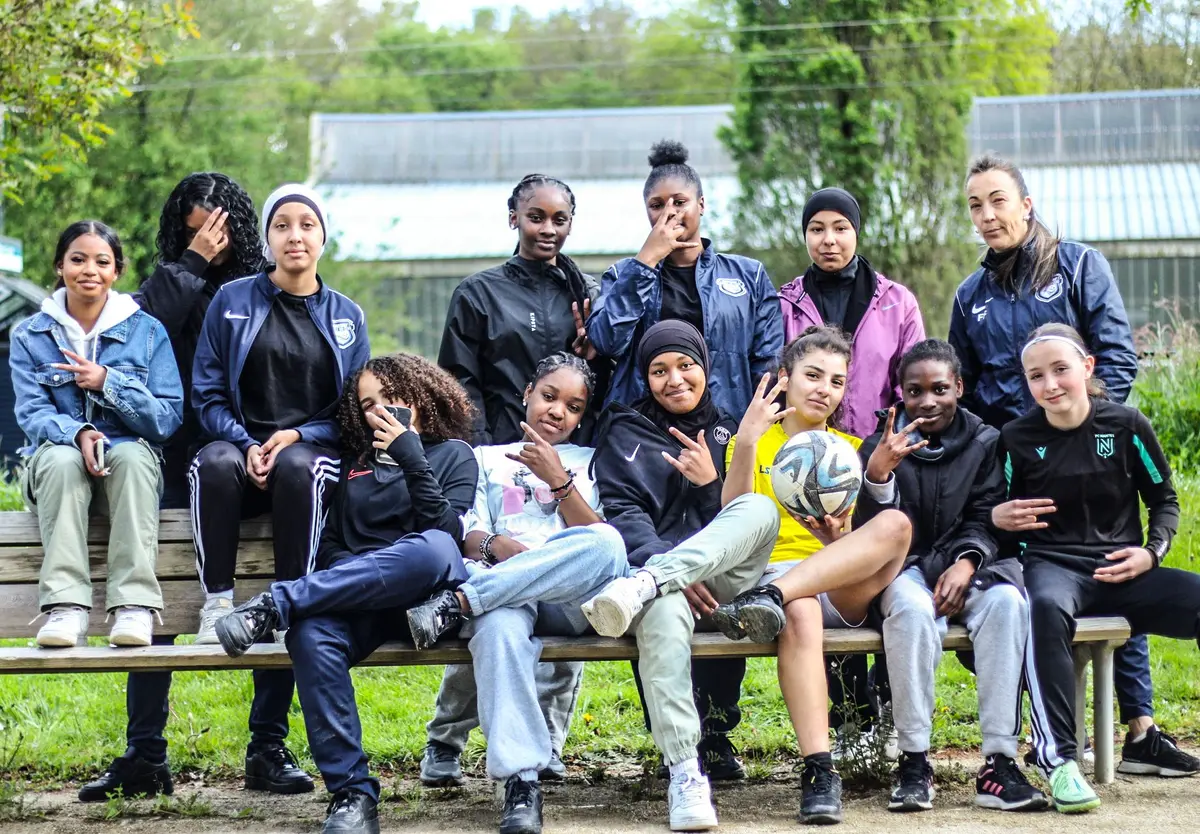Une équipe de joueuses pose sur un banc dans un parc, ballon en main