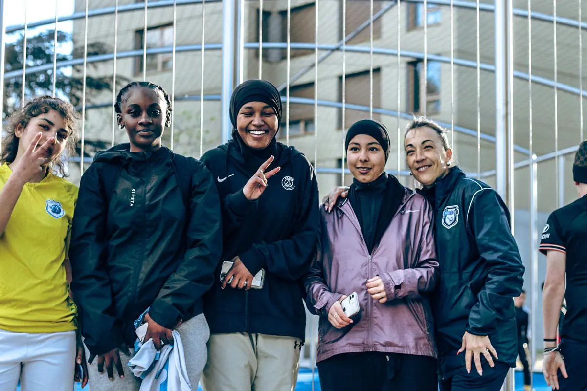 Des joueuses sourient devant les grilles du city stade