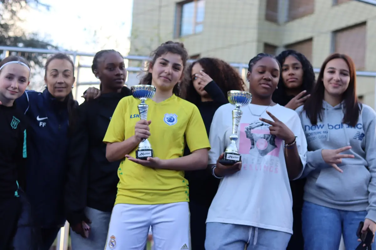 Des joueuses posent avec deux coupes au bord du city stade