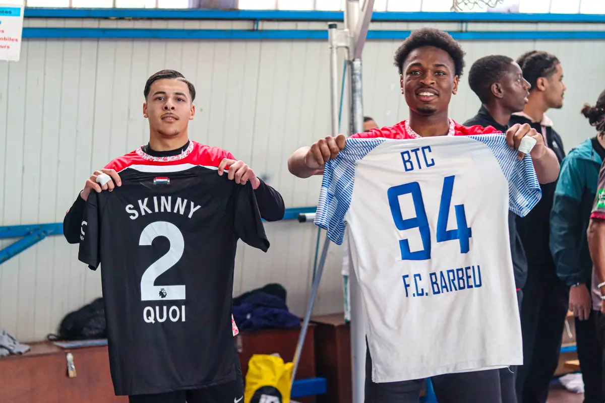 Deux joueurs en maillots rouges brandissent chacun un maillot floqué devant l'objectif