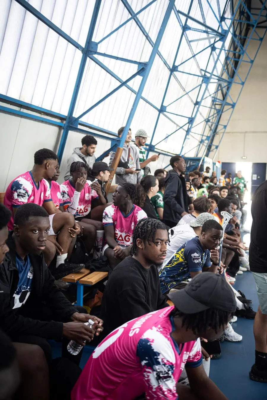Des équipes en maillots roses attendent leur match sur les bancs du gymnase
