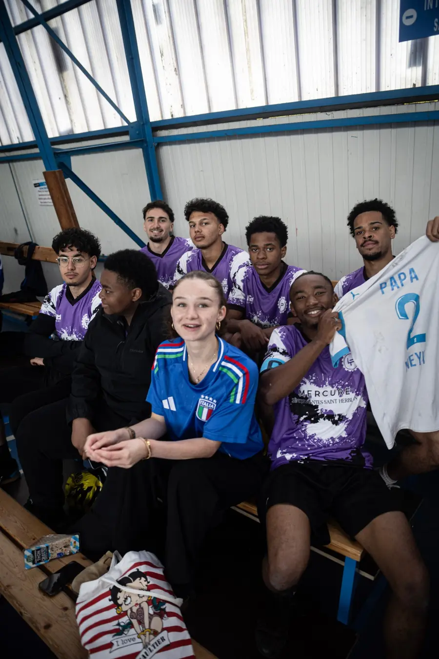 Joueurs en maillots violets et supporters sur le banc, souriants